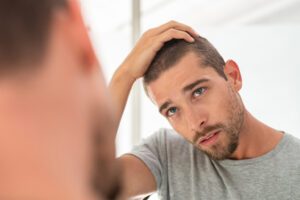 Man looking at his hair loss in the mirror