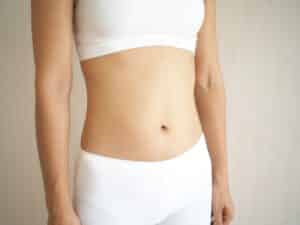 Woman in white underwear feels confident after tummy tuck.